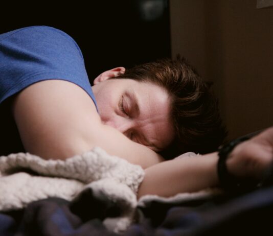 “만성 피로는 단순 피곤이 아닙니다”… 몸이 보내는 위험 신호 5가지 woman in blue shirt lying on bed